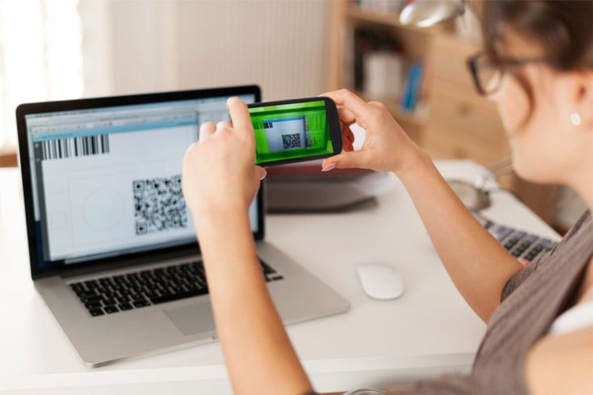 employee-scanning-laptop-qr-code-with-smartphone-in-office